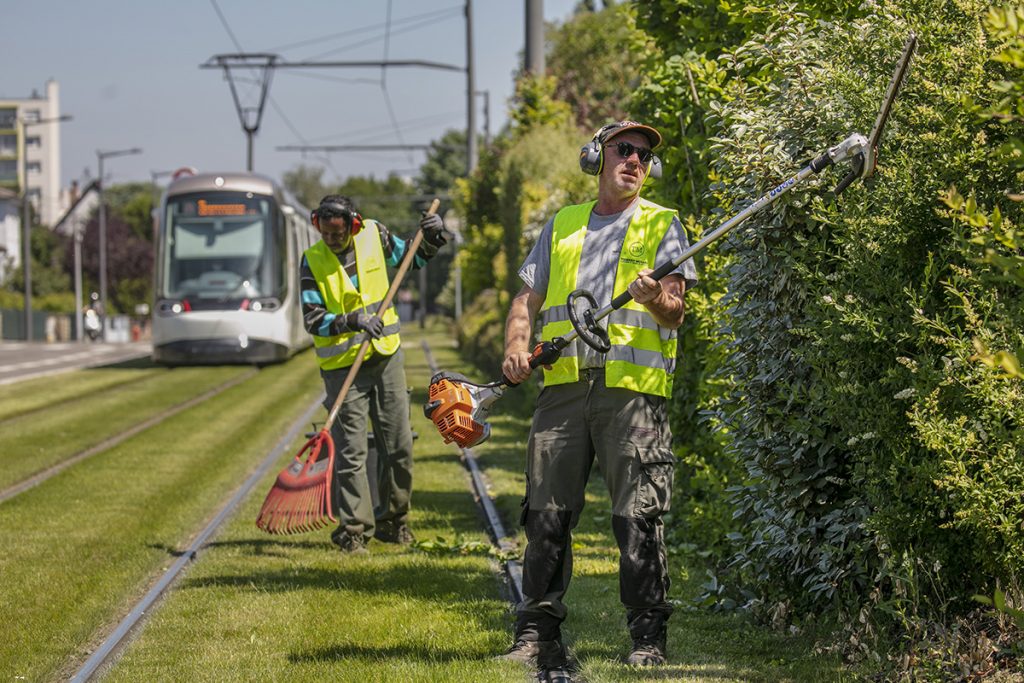 entretien d'espace vert avec tram en fond